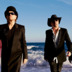 Integrantes de U2 caminando junto al mar durante una sesión fotográfica de la banda.