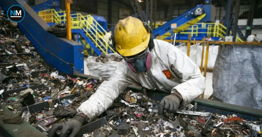 Trabajador industrial con equipo de protección clasifica materiales en una planta de procesamiento.