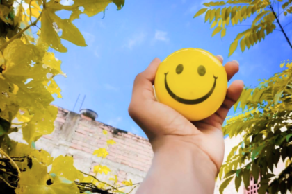 Mano sostiene una cara sonriente amarilla por el Día Mundial de la Sonrisa