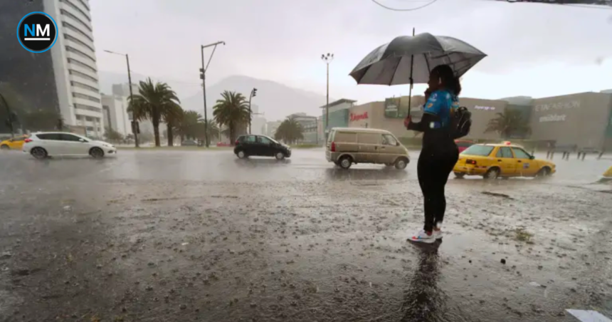 Persona con paraguas junto a una avenida de Quito durante una lluvia intensa, mientras varios vehículos circulan por la vía.