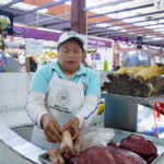 Puesto de venta de carne de res y cerdo en un mercado, con diferentes cortes exhibidos para los compradores.