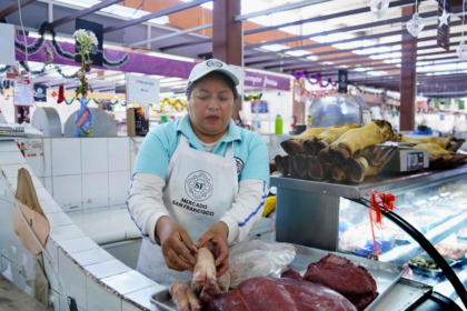 Puesto de venta de carne de res y cerdo en un mercado, con diferentes cortes exhibidos para los compradores.